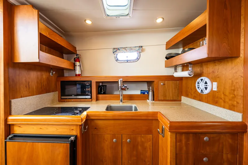 Misty Yacht Photos Pics 2007 Mainship Pilot 34 galley with wooden cabinetry, sink, stove, and microwave.