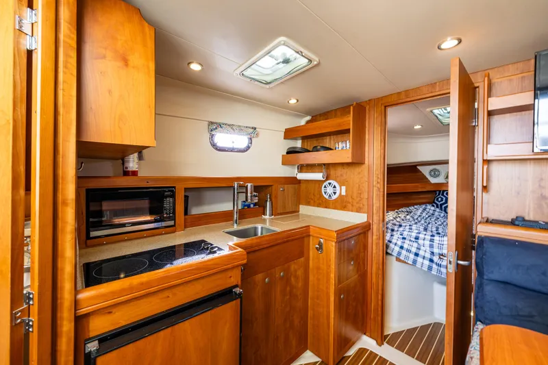 Misty Yacht Photos Pics 2007 Mainship Pilot 34 interior with kitchenette, wood cabinetry, and cozy sleeping area.
