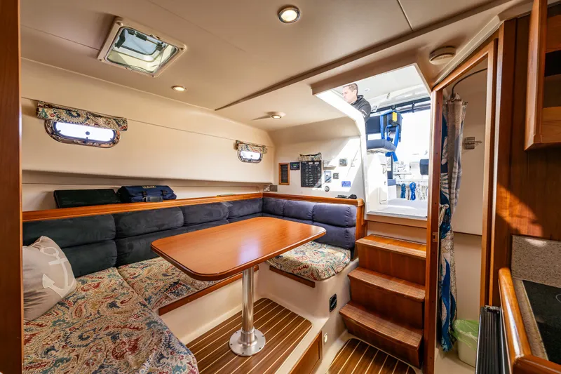 Misty Yacht Photos Pics 2007 Mainship Pilot 34 interior with cozy seating, wooden table, and steps to deck.