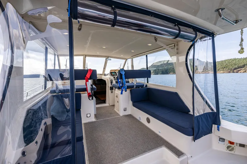Misty Yacht Photos Pics 2007 Mainship Pilot 34 interior with blue seating, clear windows, and scenic water view.