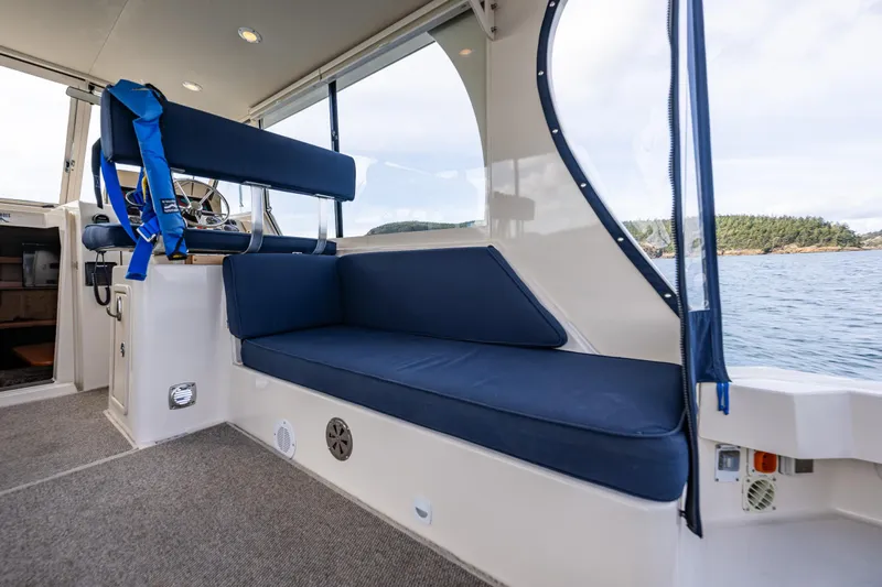 Misty Yacht Photos Pics 2007 Mainship Pilot 34 interior with blue seating, overlooking serene water and distant shoreline.