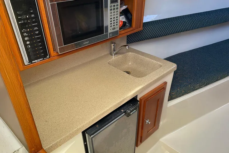Low Bid Yacht Photos Pics 2007 Albemarle 280 Express Fisherman interior with kitchenette, microwave, sink, and seating area.