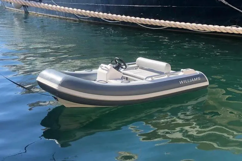 Gio Mare Yacht Photos Pics Inflatable Williams tender boat floating on calm water near a docked yacht.