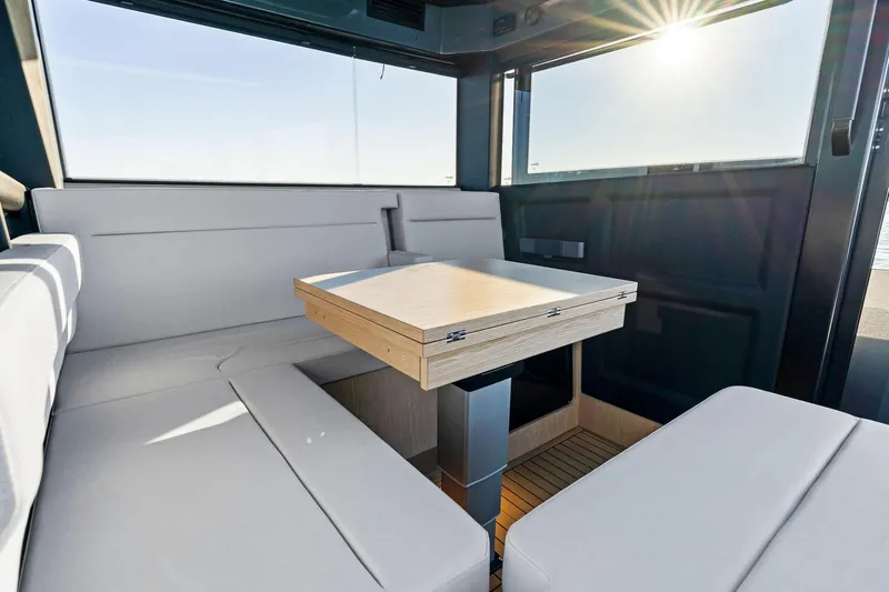  Yacht Photos Pics 2025 XO Boats EXPLR 44 interior with modern seating and wooden table, sunlit cabin.