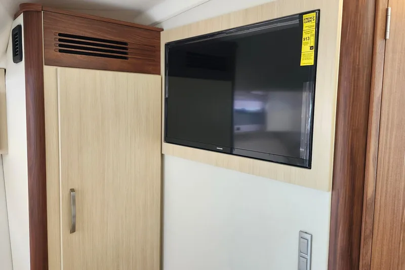  Yacht Photos Pics Flat-screen TV in 2026 Regal 36 XO yacht interior, mounted on light wood paneling.