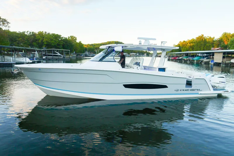 Only Fins Yacht Photos Pics 2021 Regal 38 SAV boat on a calm lake with surrounding docks and trees.