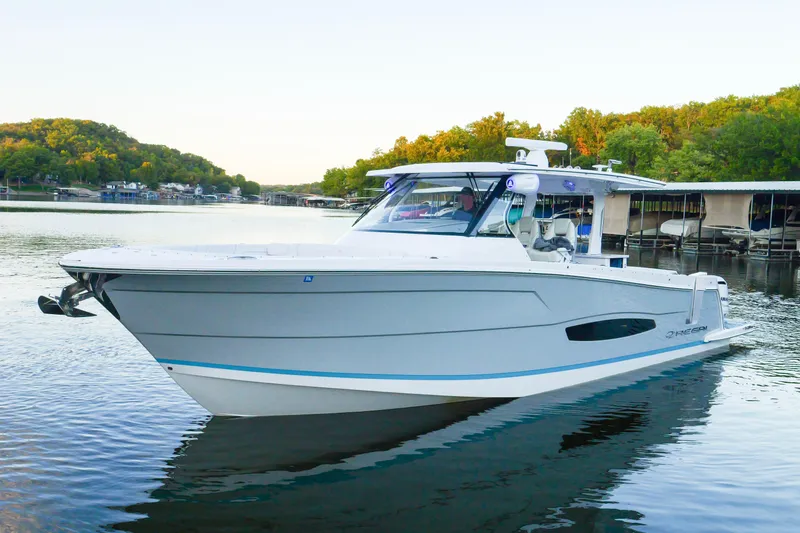 Only Fins Yacht Photos Pics 2021 Regal 38 SAV boat on calm water, surrounded by lush greenery and docks.