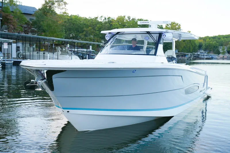 Only Fins Yacht Photos Pics 2021 Regal 38 SAV boat on calm water, surrounded by lush greenery.