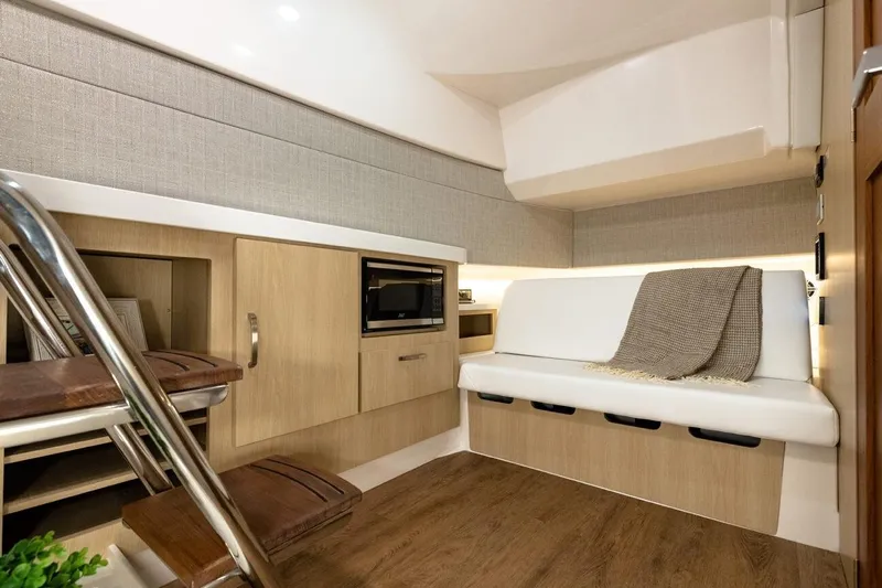 Only Fins Yacht Photos Pics 2021 Regal 38 SAV interior with modern seating, wooden cabinetry, and a cozy blanket.