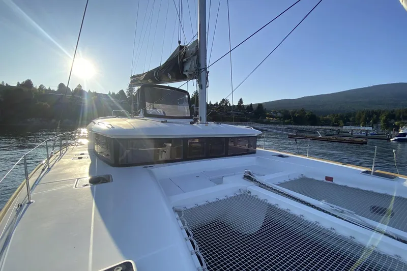 Why Not Yacht Photos Pics 2019 Lagoon 450F catamaran sailing at sunset near a scenic shoreline.