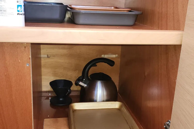 Why Not Yacht Photos Pics Wooden cabinet with kettle, baking trays, and coffee dripper in Lagoon 450F yacht kitchen.