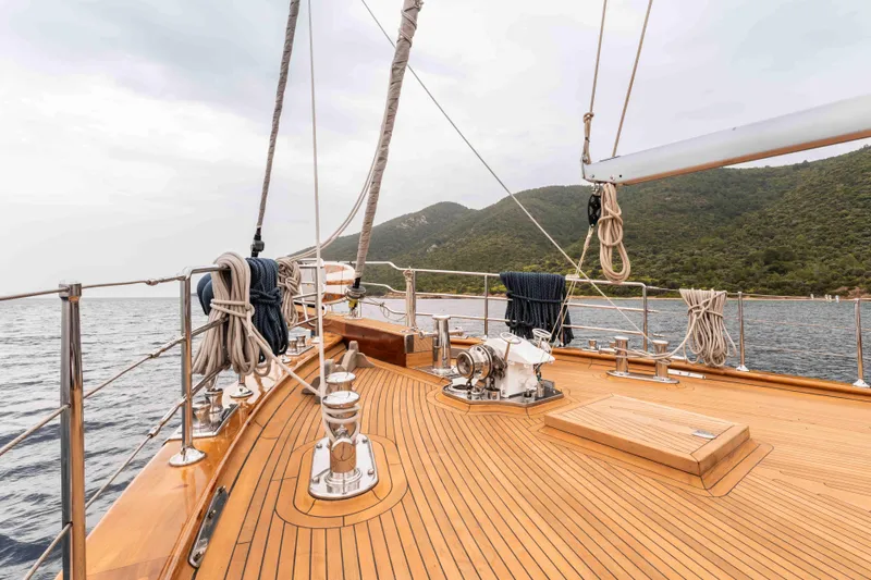 Le Pietre Yacht Photos Pics Custom 2009 sailing yacht with wooden deck, sailing near a mountainous coastline.