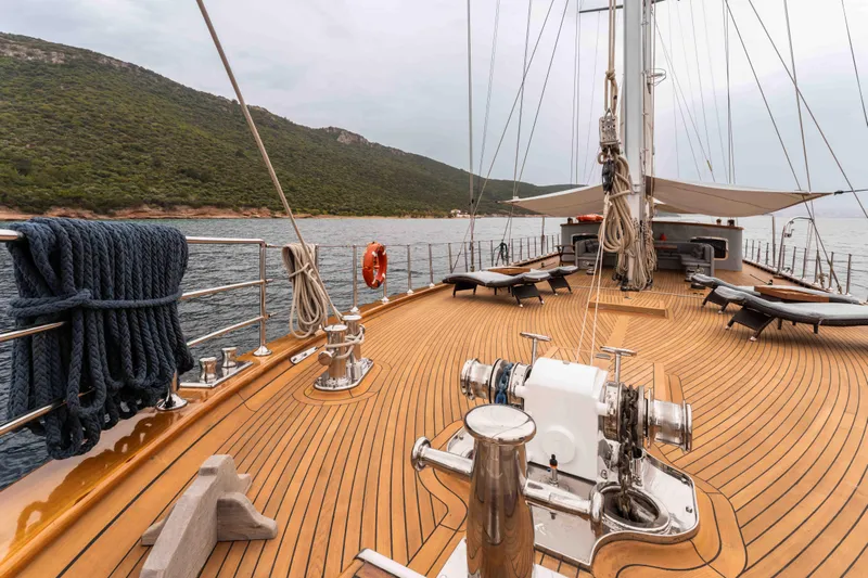 Le Pietre Yacht Photos Pics Custom 2009 sailing yacht with wooden deck, anchored near a lush green coastline.