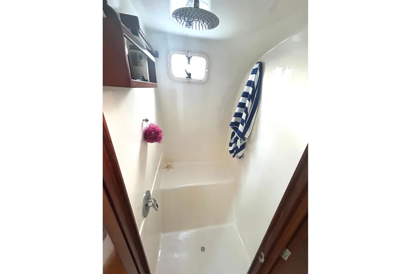 Jonny Wasabi Yacht Photos Pics Shower area in 2002 Custom 64 Stuart Catamarans, featuring a window and striped towel.