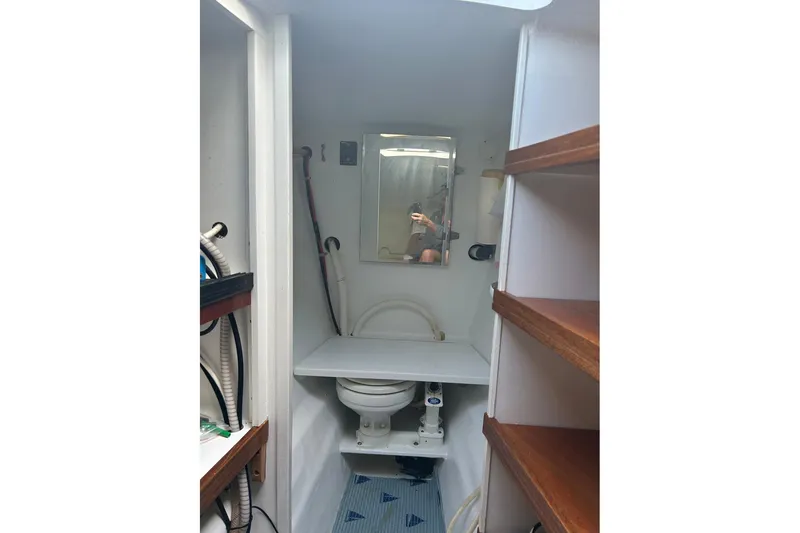 Jonny Wasabi Yacht Photos Pics Compact bathroom on 2002 Custom 64 Stuart Catamarans, featuring toilet, mirror, and shelving.