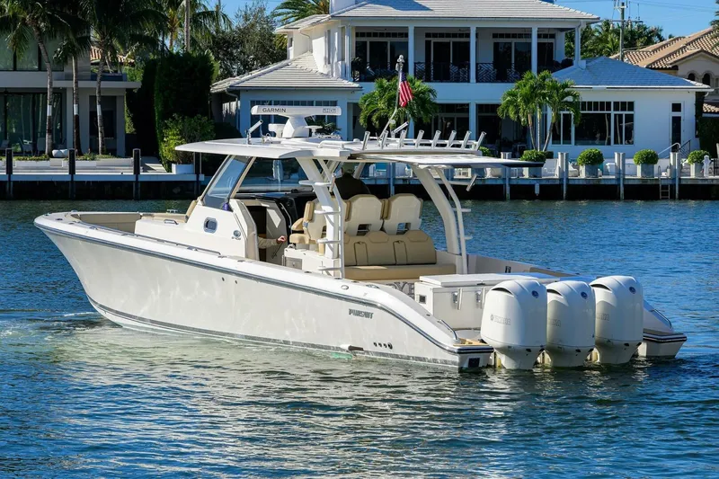 Leap Year Yacht Photos Pics 2018 Pursuit S 408 Sport boat cruising on a sunny waterfront near luxury homes.