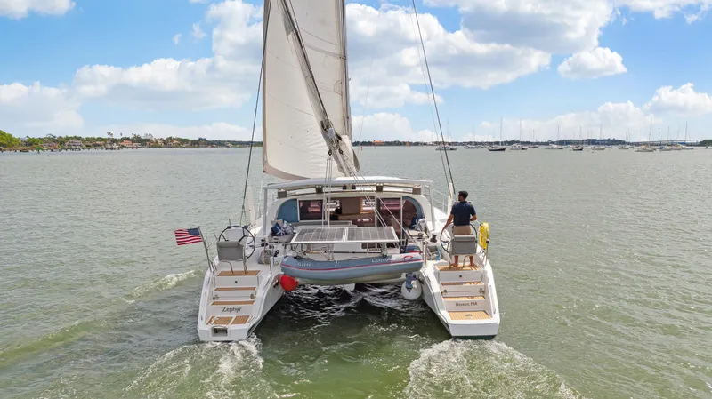 Zephyr Yacht Photos Pics Catana 42 catamaran sailing on open water, 2016 model, rear view with American flag.