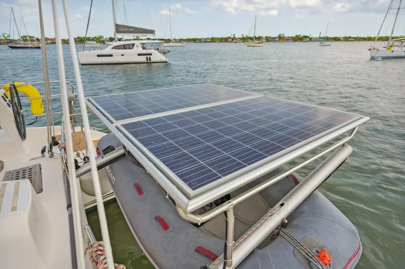 Zephyr Yacht Photos Pics Catana 42 catamaran with solar panels and dinghy, anchored in a scenic bay.