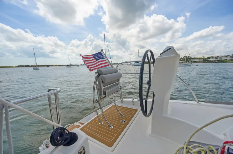 Zephyr Yacht Photos Pics Catana 42 sailboat deck with American flag, steering wheel, and scenic water view.