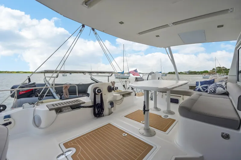 Zephyr Yacht Photos Pics Spacious deck of 2016 Catana 42 catamaran with seating and table, overlooking serene waters.