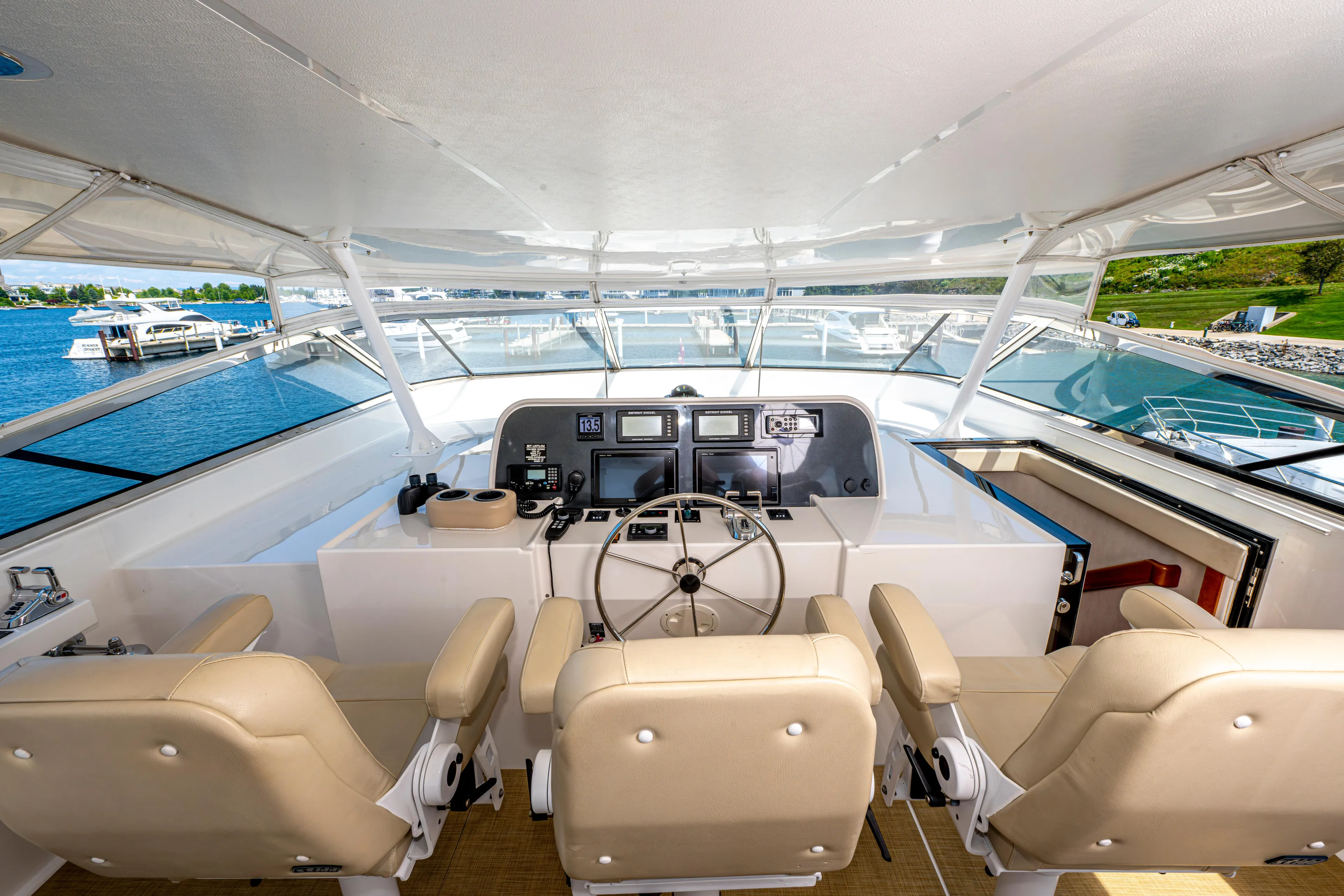  Yacht Photos Pics Helm station of 2005 Pacific Mariner 85 Motor Yacht with beige seats and navigation equipment.