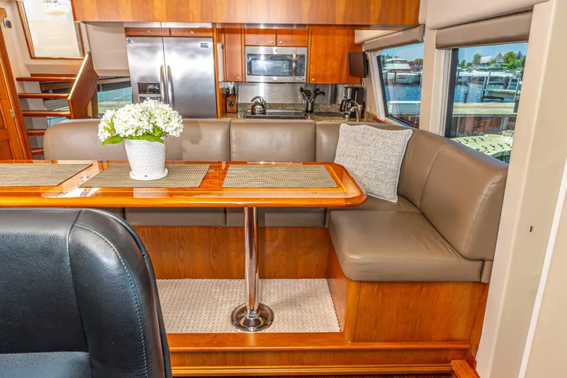  Yacht Photos Pics 2005 Pacific Mariner 85 Motor Yacht interior dining area with table, seating, and kitchen appliances.