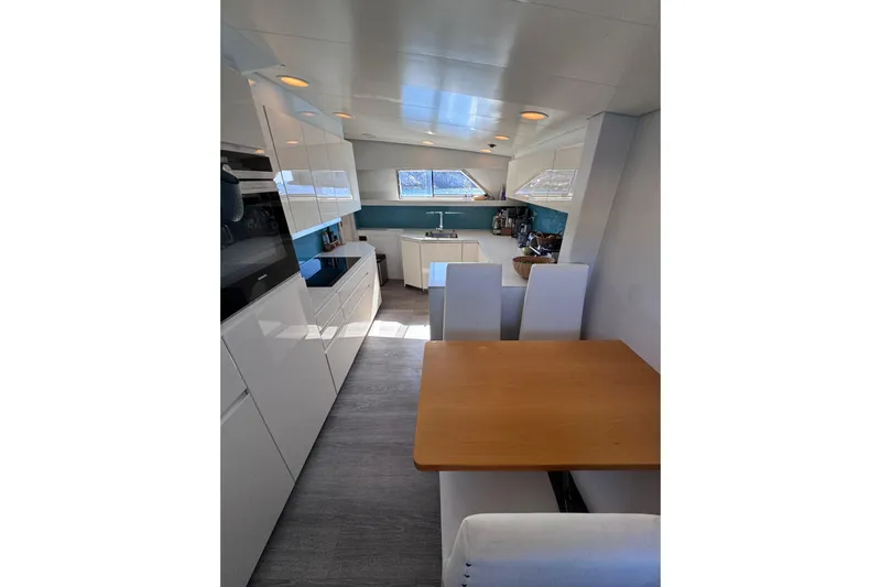  Yacht Photos Pics Modern kitchen interior on 2000 Sanlorenzo SL88 yacht, featuring sleek white cabinetry and dining area.