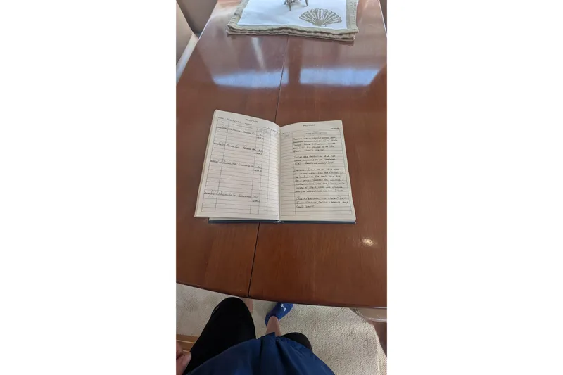 High Flyer Yacht Photos Pics Open logbook on a polished wooden table inside a 2007 Meridian 411 Sedan Bridge.