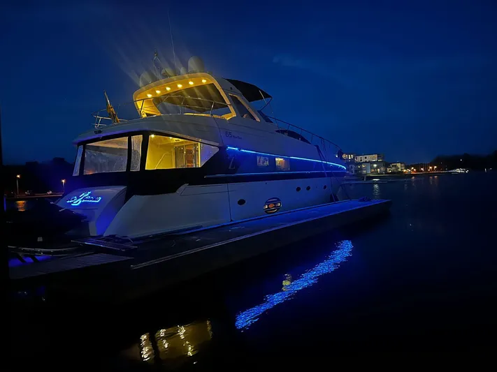  Yacht Photos Pics 2009 Conam 65 Flybridge yacht illuminated at night with blue lights on the water.