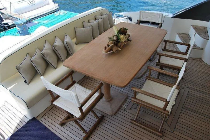  Yacht Photos Pics Luxurious dining area on 2009 Conam 65 flybridge yacht with wooden table and cushioned seating.