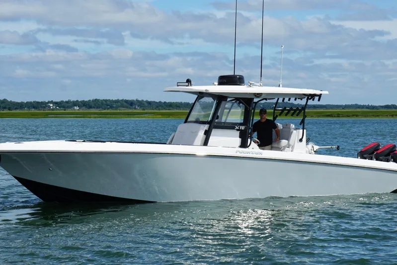  Yacht Photos Pics 2024 Fountain 34 TE boat cruising on a calm lake under a partly cloudy sky.