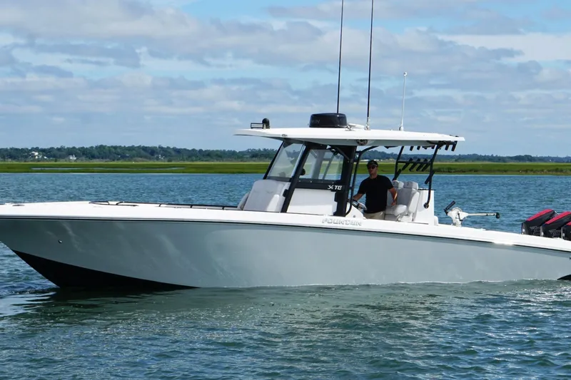  Yacht Photos Pics 2024 Fountain 34 TE boat cruising on a calm lake under a blue sky.