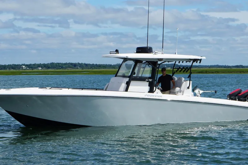  Yacht Photos Pics 2024 Fountain 34 TE boat cruising on a calm lake under a partly cloudy sky.