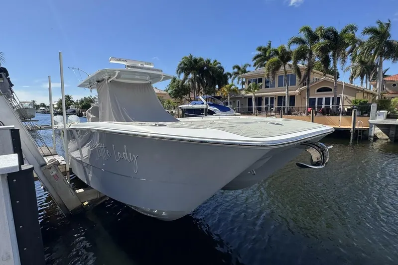 Little Lady Yacht Photos Pics 2024 Invincible 35 Catamaran docked by waterfront homes, under clear blue sky.