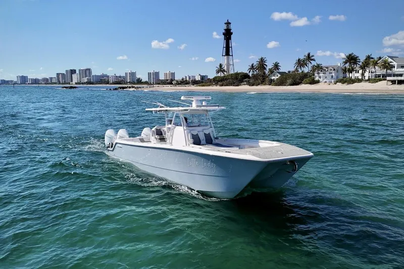 Little Lady Yacht Photos Pics 2024 Invincible 35 Catamaran cruising near a lighthouse and beachfront cityscape.