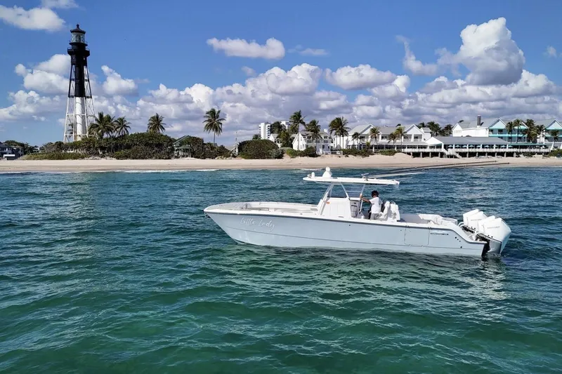 Little Lady Yacht Photos Pics 2024 Invincible 35 Catamaran cruising near a lighthouse and beachside homes.