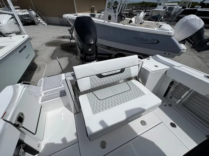 252 - 457 Yacht Photos Pics 2025 Blackfin 252 CC boat interior with seating and outboard motor in a marina setting.