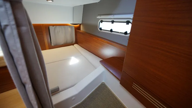 In-stock 2024 Nimbus 305 Coupé #393 Yacht Photos Pics Cozy cabin interior of 2024 Nimbus 305 Coupe #393 with wooden accents and a window.