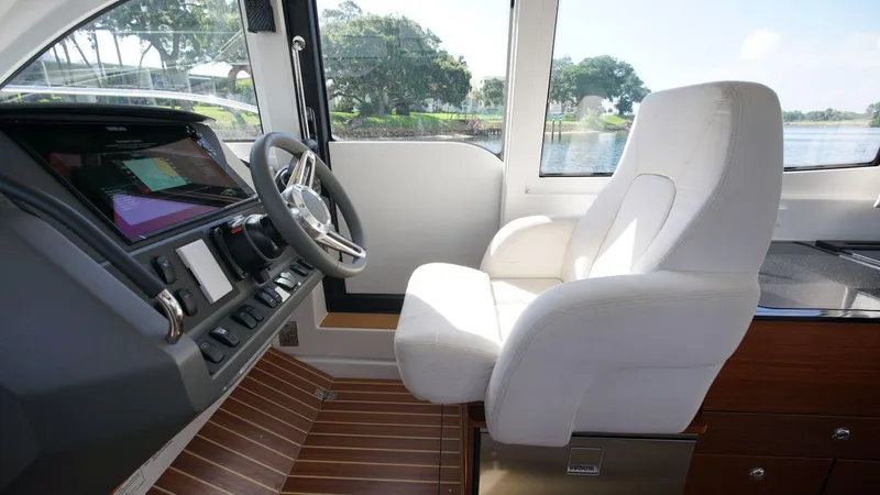 In-stock 2024 Nimbus 305 Coupé #393 Yacht Photos Pics Interior helm of 2024 Nimbus 305 Coupe #393 with white captain's chair and modern controls.