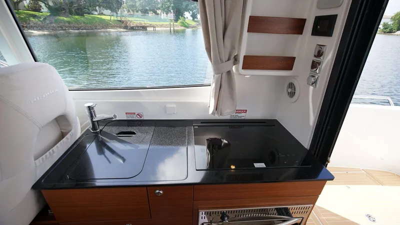 In-stock 2024 Nimbus 305 Coupé #393 Yacht Photos Pics 2024 Nimbus 305 Coupe #393 interior kitchen with sink and stove, overlooking water.