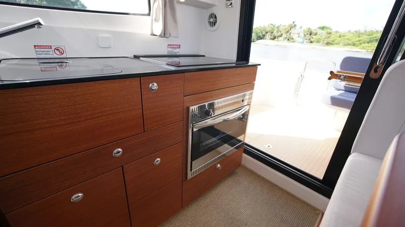 In-stock 2024 Nimbus 305 Coupé #393 Yacht Photos Pics 2024 Nimbus 305 Coupe #393 kitchen area with modern appliances and outdoor view.