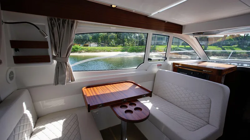 In-stock 2024 Nimbus 305 Coupé #393 Yacht Photos Pics Interior of 2024 Nimbus 305 Coupe #393 with seating and table, window view.