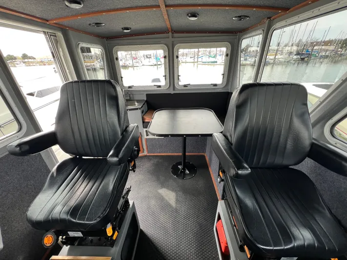  Yacht Photos Pics Interior of 2021 Velocity LC3311 boat with two black seats and a table.