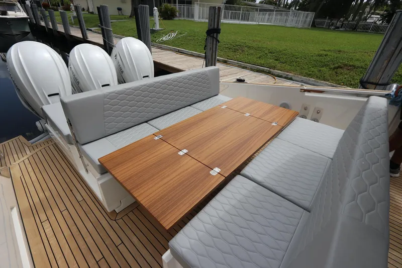  Yacht Photos Pics 2024 Astondoa 377 Coupe Outboard with sleek seating and wooden table on deck.