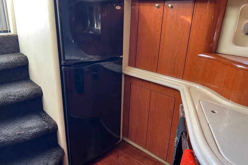  Yacht Photos Pics Interior of 1998 Sea Ray 540 Sundancer yacht with wood cabinetry and black refrigerator.