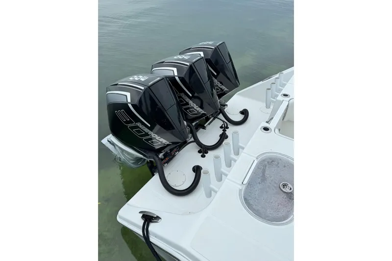  Yacht Photos Pics Triple outboard motors on a 2022 SeaHunter 33 Tournament boat, docked on calm water.
