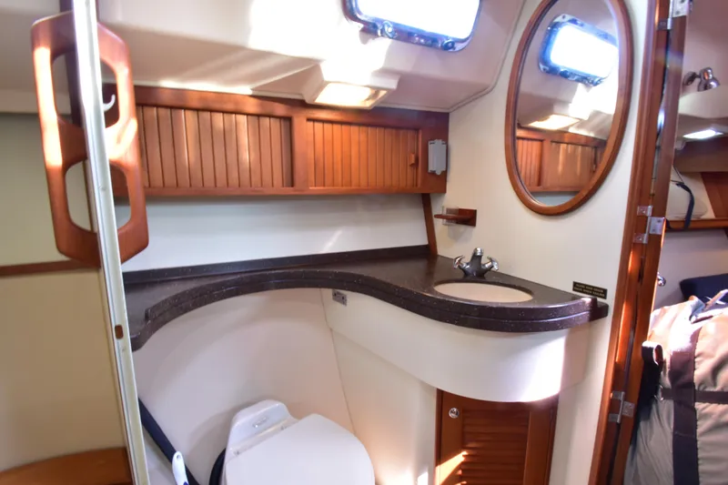 Chinook Yacht Photos Pics 2004 Island Packet 485 yacht bathroom with sink, mirror, and wooden cabinetry.