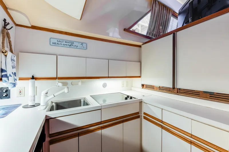  Yacht Photos Pics 1990 Bertram 50 Convertible yacht kitchen with modern white cabinetry and sink.