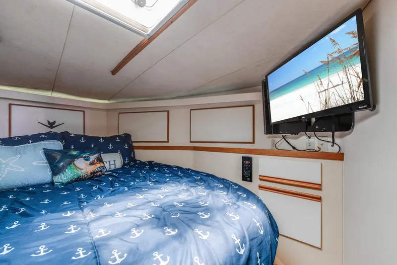  Yacht Photos Pics Cozy bedroom in 1990 Bertram 50 Convertible yacht with nautical decor and wall-mounted TV.