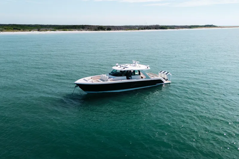 Phoenix Yacht Photos Pics 2023 Tiara 48 yacht cruising on calm blue waters near a scenic coastline.